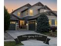 Charming two-story home boasts dual garages and attractive curb appeal in a tranquil neighborhood at dusk at 10681 Sundial Rim Rd, Highlands Ranch, CO 80126
