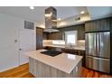 Modern kitchen boasts stainless steel appliances, center island with cooktop, and stylish wood cabinets at 3404 W 18Th Ave, Denver, CO 80204