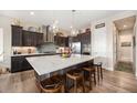 Modern kitchen featuring dark cabinets, stainless steel appliances, and a large center island with barstool seating at 11168 Sweet Cicely Dr, Parker, CO 80134