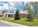 Well-manicured lawn and mature trees surrounding a charming red brick ranch style home with a two-car garage at 6086 W Arizona Ave, Lakewood, CO 80232