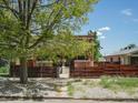 Charming brick home surrounded by mature tree, featuring a decorative wooden fence at 3914 Osage St, Denver, CO 80211