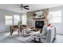 Bright living room featuring a stone fireplace, neutral furniture, and large windows for natural light at 12631 W Dakota Dr, Lakewood, CO 80228