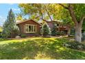 Charming home featuring brick and wood siding, lush lawn, and mature trees at 7346 S Platte Canyon Dr, Littleton, CO 80128