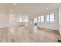 Spacious living room featuring wood floors, white walls, recessed lighting, large windows, and a sliding glass door at 8846 Waterleaf Ln, Littleton, CO 80125
