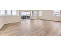 Bright living room featuring sleek wood-look floors, large windows, and sliding glass doors to a balcony at 8846 Waterleaf Ln, Littleton, CO 80125