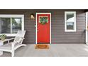 Inviting front porch featuring a red door with wreath, 'Welcome' doormat, and a comfortable lounge chair at 800 S Krameria St, Denver, CO 80224