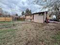 A home's spacious backyard with chain link and wood fencing, grass and dirt, on an overcast day at 5363 W 4Th Ave, Lakewood, CO 80226