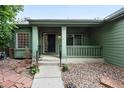 Inviting front porch with green trim, a black front door, and well-maintained landscaping at 2130 Chestnut Cir, Erie, CO 80516