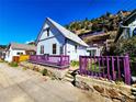 Charming cottage with a purple-trimmed porch nestled against a hillside, offering unique curb appeal and character at 1716 Virginia St, Idaho Springs, CO 80452