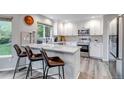 Bright kitchen featuring white cabinetry, modern stainless steel appliances, a breakfast bar, and quartz countertops at 12430 S Downy Creek Ct, Parker, CO 80134