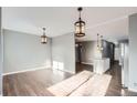 Spacious living room featuring hardwood floors, neutral gray walls, and stylish pendant lighting, connecting to a kitchen area at 530 Hickory St, Hudson, CO 80642