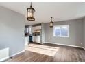 Open-concept living room with hardwood floors, seamlessly connecting to a kitchen with stainless steel appliances and white cabinetry at 530 Hickory St, Hudson, CO 80642