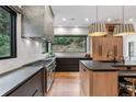 Modern kitchen featuring stainless steel appliances, dark cabinets, and large window with lush greenery view at 6123 Buffalo Run, Littleton, CO 80125