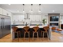 Modern kitchen with stainless steel appliances, white cabinets, kitchen island, wooden stools, and globe pendant lighting at 2248 S Lincoln St, Denver, CO 80210