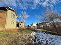 Landscaped backyard of a split-level home with a partially snow-covered yard at 6861 Oberon Rd, Arvada, CO 80004