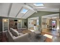 Bright living room featuring vaulted ceilings with skylights, hardwood floors, and views into the kitchen and dining area at 6684 E Bates Ave, Denver, CO 80224