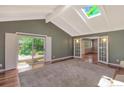 Sunlit living room with skylights, hardwood floors, and sliding doors opening to the deck at 6684 E Bates Ave, Denver, CO 80224
