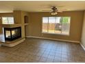 This vacant living room features a fireplace, ceiling fan, tile floors, and a large window overlooking the yard at 20787 E 39Th Ave, Denver, CO 80249