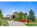 Beautifully landscaped home with stone accents and a lush front yard featuring colorful shrubs and a curved driveway at 5608 Raintree Dr, Parker, CO 80134