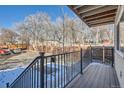 Backyard view from porch, showcasing a wooden deck, black metal railing, and fenced yard surrounded by mature trees at 6021 Yarrow St # B13, Arvada, CO 80004