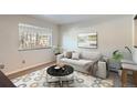 Well-lit living room features a cozy sofa, round table, and view of the outside through a bright window at 6021 Yarrow St # B13, Arvada, CO 80004