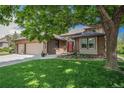 Charming brick home with a well-manicured lawn, mature tree, and attached three-car garage at 1152 Clubhouse Dr, Broomfield, CO 80020