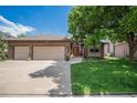 Charming brick home with a well-manicured lawn, mature tree, and attached three-car garage at 1152 Clubhouse Dr, Broomfield, CO 80020