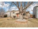 Charming tan two-story home with an orange front door and a large mature tree in the front yard at 4314 Nepal St, Denver, CO 80249