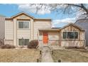 Charming tan two-story home with an orange front door and a well-manicured lawn with mature trees at 4314 Nepal St, Denver, CO 80249