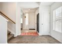 Bright foyer with tile flooring, carpeted staircase and a white front door at 19047 Randolph Pl, Denver, CO 80249