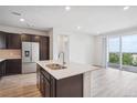Modern kitchen featuring dark cabinetry, stainless steel appliances, a kitchen island and sliding glass door to the balcony at 487 Interlocken Blvd # 303, Broomfield, CO 80021