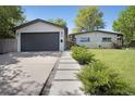 Inviting home exterior boasts a gray garage door, concrete path, and lush green bushes at 9400 Ridge Rd, Arvada, CO 80002
