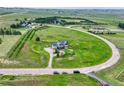 Aerial view of gray two-story home with solar panels on a large lot surrounded by green fields at 43793 Buckskin Rd, Parker, CO 80138