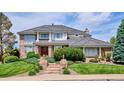 Beautiful brick home with a well-maintained lawn, brick stairs, and a red front door at 15573 E Prentice Ln, Centennial, CO 80015