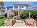 Stately brick home with a red front door, brick pillars and steps, and lush landscaping at 15573 E Prentice Ln, Centennial, CO 80015