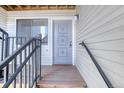 Close up of the front door with wood porch and decorative metal railings, modern lock, and doorbell at 6007 Yarrow St # D, Arvada, CO 80004