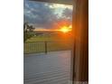 View from sliding glass door onto back deck area with sunset over distant green field with fence at 46531 Sundance Trl, Parker, CO 80138