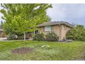 Well-maintained front yard with mature trees and landscaping, leading to a classic brick home at 6046 Vrain St, Arvada, CO 80003