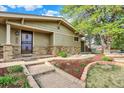 Close-up of the home's entrance showcasing the stone facade and neatly landscaped flower beds at 7895 W 67Th Ave, Arvada, CO 80004