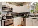 Fully equipped kitchen with stainless steel appliances, mosaic backsplash, and white cabinets at 8422 S Upham Way # H75, Littleton, CO 80128
