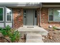Welcoming front entrance with brick exterior, gray door, and manicured landscaping at 7114 E Briarwood Dr, Centennial, CO 80112