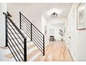 Staircase with wooden steps, black metal railing and light hardwood floors leading into the home at 6889 Frying Pan Rd, Boulder, CO 80301