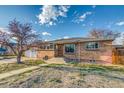 Brick front ranch home with a two-car garage on a sunny day with blue skies and an unfinished yard at 6095 W 47Th Ave, Wheat Ridge, CO 80033