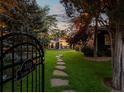 Home's backyard with black metal gate, lush green grass, stone pathway and string lights at 3339 Lowell Blvd, Denver, CO 80211