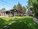 Spacious backyard with lush green grass, stone pathway, barbecue and garage with trim at 3339 Lowell Blvd, Denver, CO 80211