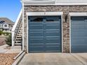 Attached garage with a blue door, stone facade, and convenient access via nearby exterior staircase at 5755 S Buchanan Ct # E, Aurora, CO 80016