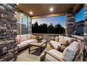 Covered patio with stone wall and comfortable seating area at 147 Chapel Hill Cir, Brighton, CO 80601