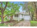 Attractive home with a detached garage and a well-maintained driveway nestled amid established trees and landscaping at 6260 W 45Th Pl, Wheat Ridge, CO 80033
