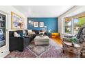 Bright living room with a blue accent wall, plush seating, and a large bay window at 7034 S Cherry St, Centennial, CO 80122