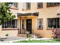 Apartment entrance with a brick facade, black trim, and maintained front yard with lawn and mature tree at 1160 Birch St # 22, Denver, CO 80220